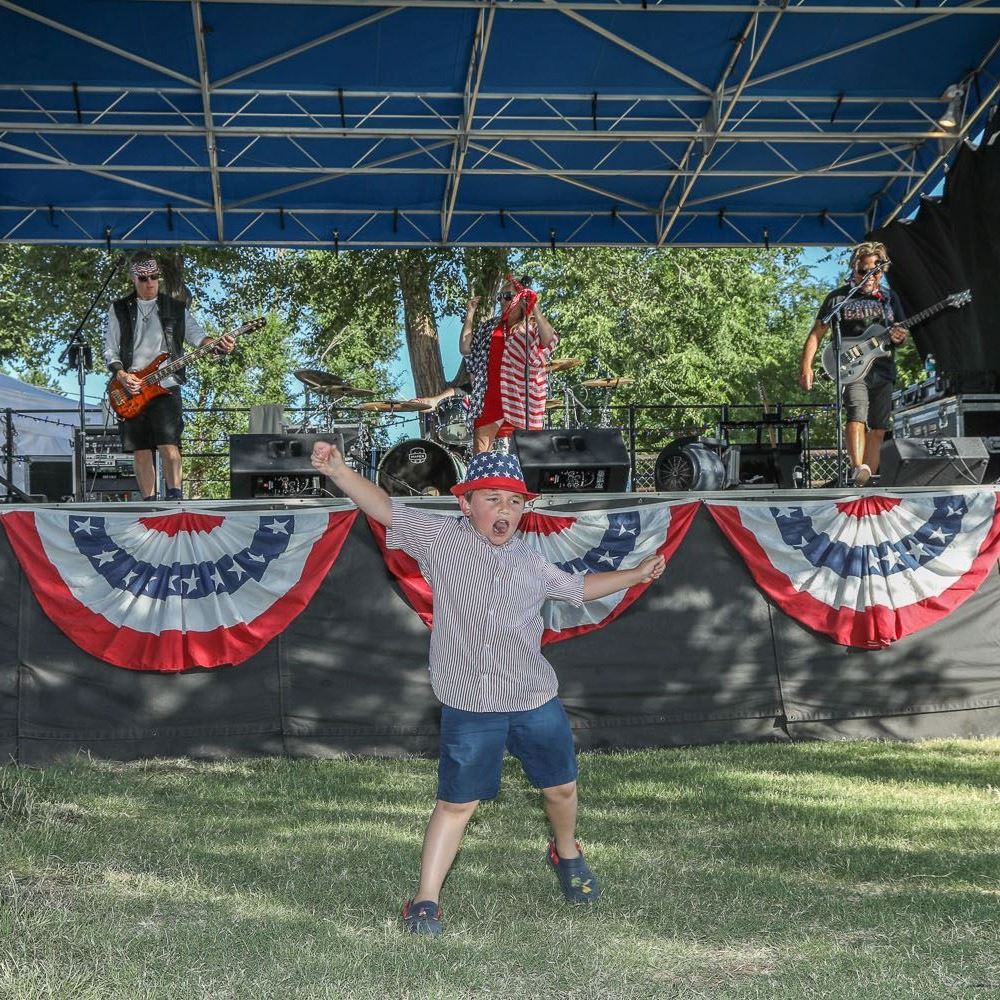 Young Child dances in front of stage while band plays at Freedom Fest.